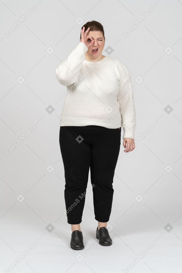 Mujer de talla grande en ropa casual mirando a través de los dedos