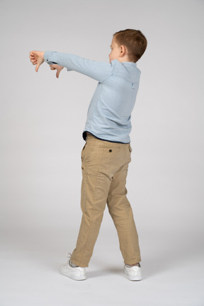 Vista trasera de un niño mostrando los pulgares hacia abajo