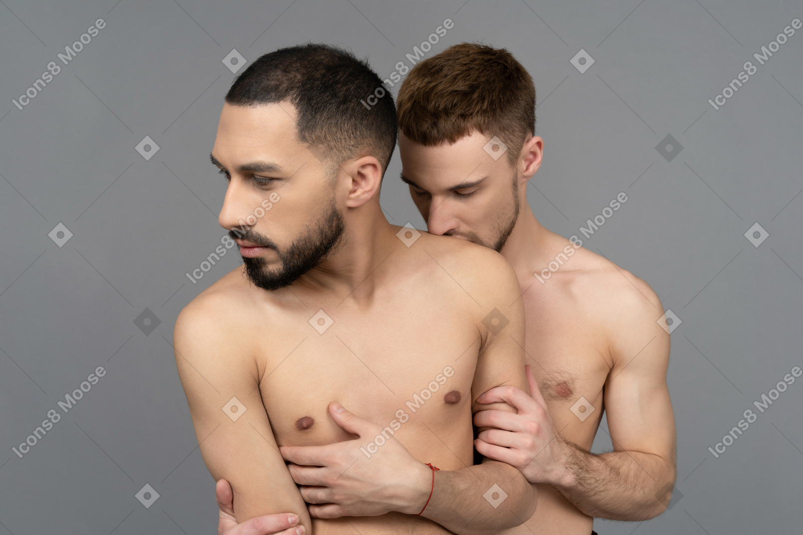 Close-up of a young caucasian man kissing shoulder of his shirtless partner from behind