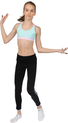 Front view of a teen girl in sportswear raising hands and dancing