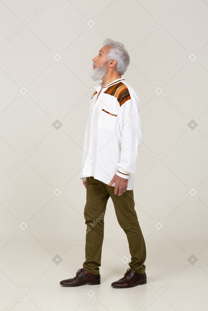 Side view of gray-haired man walking and looking up
