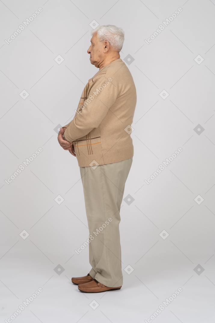 じっと立っているカジュアルな服装の老人の側面図