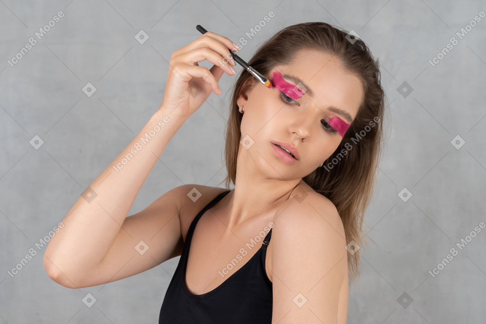 Portrait of a young woman putting eyeshadow on
