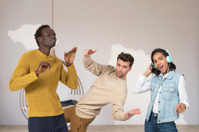 Un groupe de jeunes amis multiculturels dansant au son de la musique dans une salle lumineuse au style minimaliste