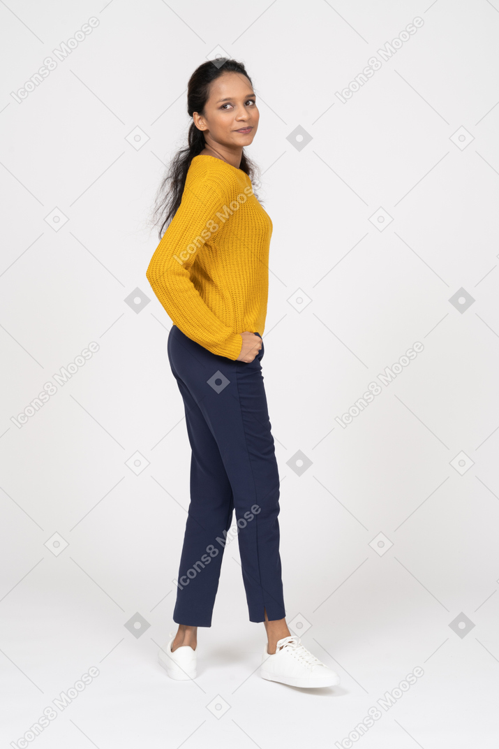 Side view of a cute girl posing with hand on hip and looking at camera