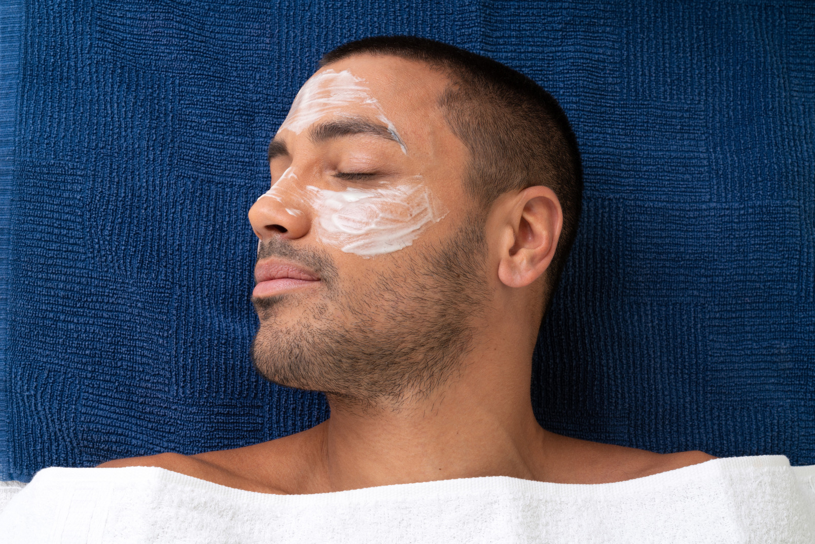 Young man with facial mask lying with his eyes closed