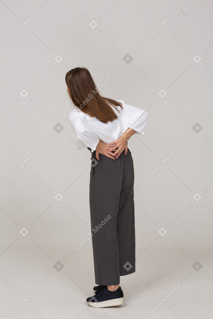 Три четверти сзади молодой леди в офисной одежде с болями в спине