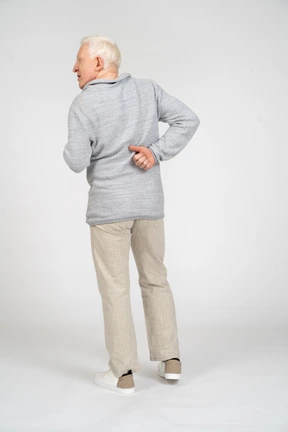 Back view of a man standing with thumbs up behind his back and looking away