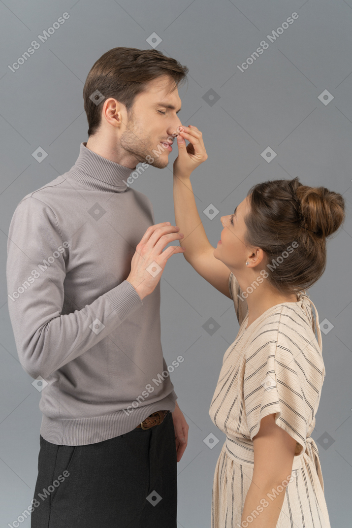 年轻女子捏她男朋友的鼻子