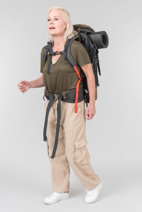 Mature female tourist carrying heavy backpack and kind of gasping