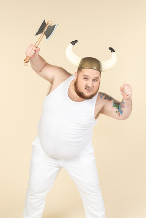 An emotional plus-sized man in white with a horned helmet on his head, holding a double-bladed axe