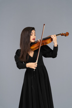 Close-up de uma jovem de vestido preto tocando violino