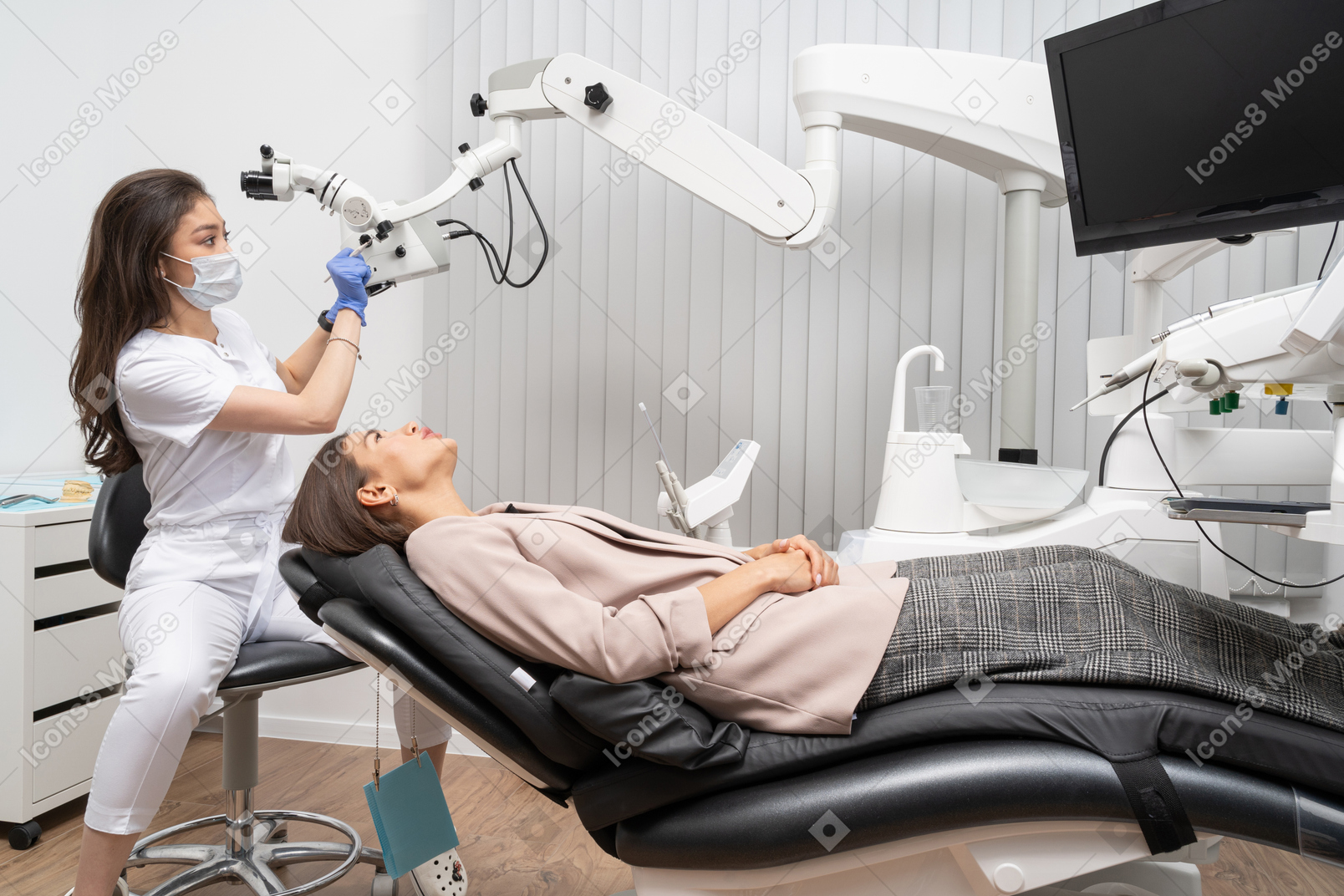 Женщина-стоматолог в полный рост заканчивает стоматологическое обследование своей пациентки