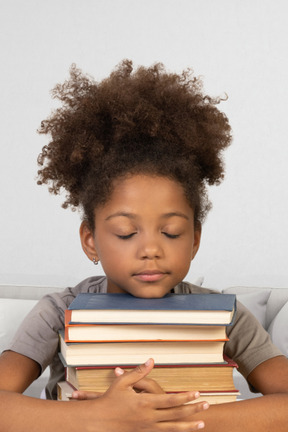 Little girl holding a bunch of books with her eyes closed