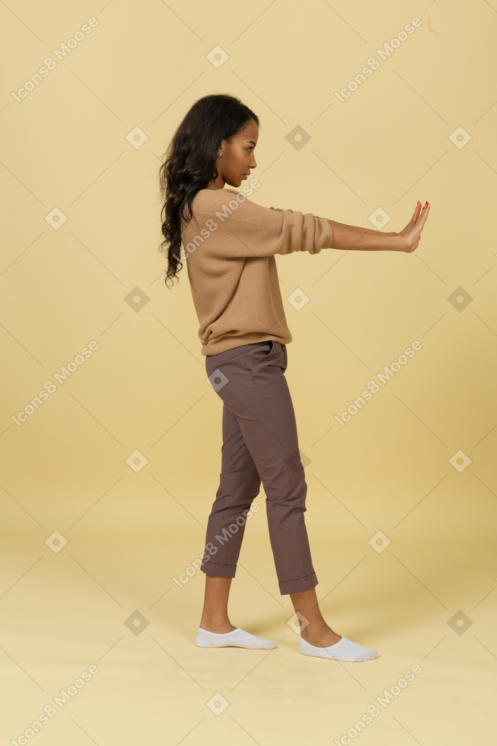 Side view of a dark-skinned young female outstretching hands