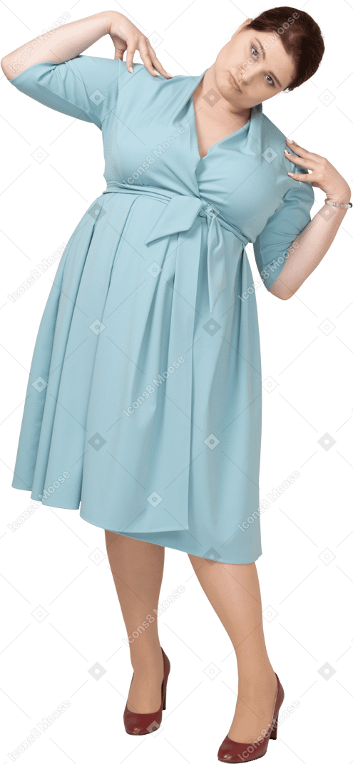 Вид спереди женщины в голубом платье, стоящей с руками на плечах