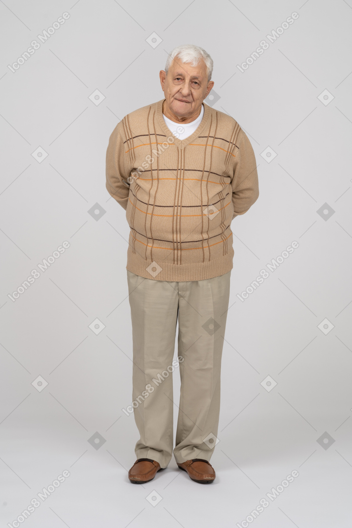 Vorderansicht eines alten mannes in freizeitkleidung, der mit den händen hinter dem rücken steht