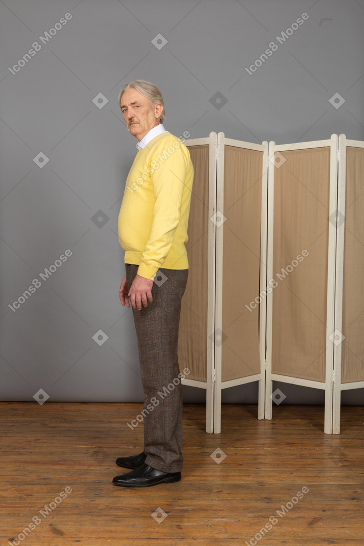 Side view of an old man standing still looking at camera