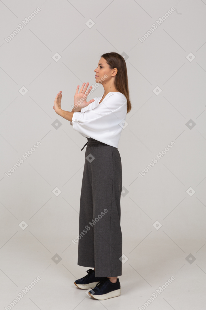 Vista lateral de una señorita en ropa de oficina cruzando los brazos
