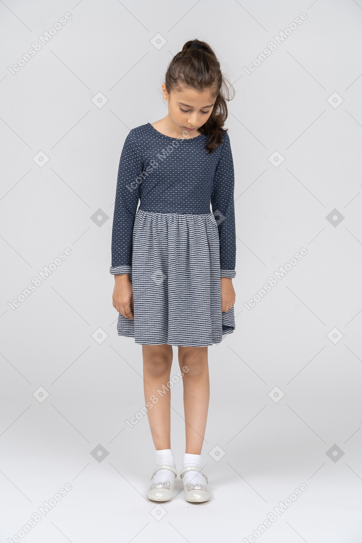 Vista frontal de una niña de pie con la cabeza hacia abajo