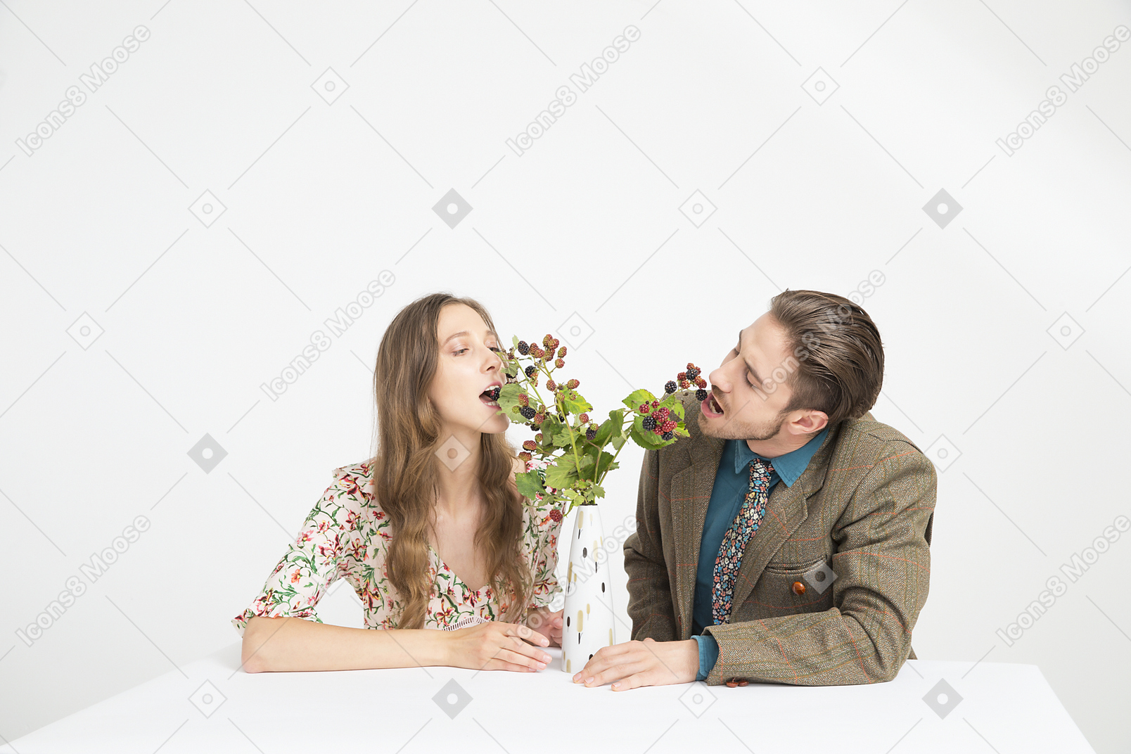 Couple sitting at the table and eating blackberries from the branches in vase