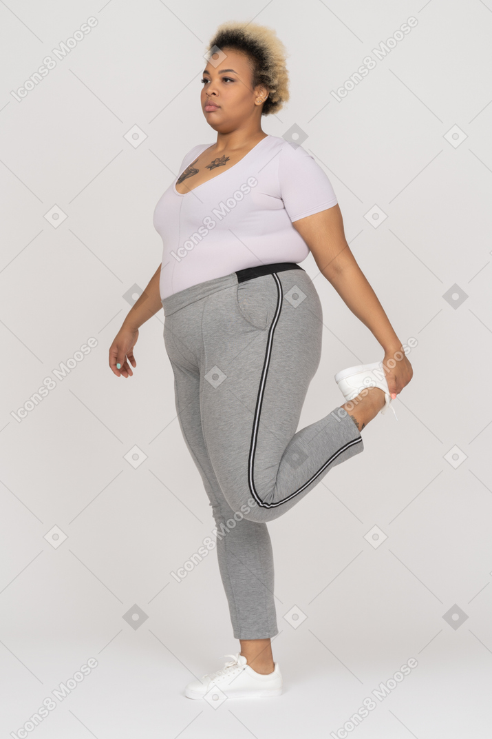 Пухлая темнокожая женщина балансирует на одной ноге