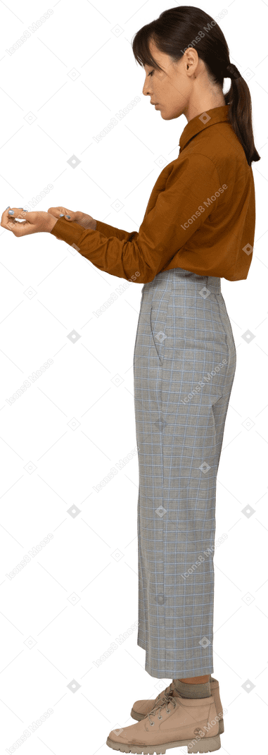 Vista laterale di una giovane donna asiatica in calzoni e camicetta che si abbottona il polsino
