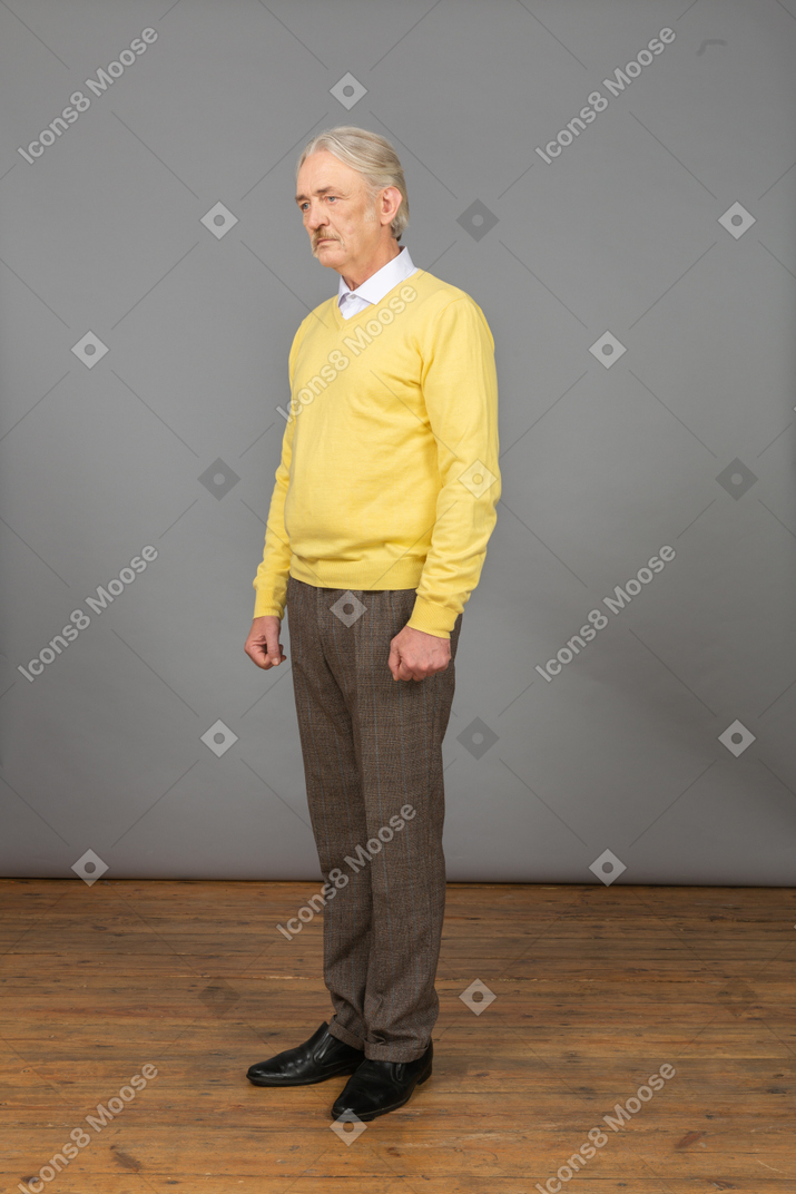 Вид в три четверти депрессивного старика в желтом пуловере, смотрящего в сторону