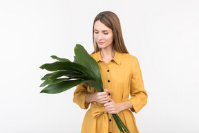 Young woman holding green leaves