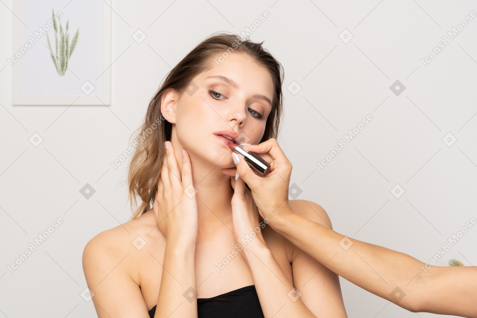 Vista frontal de un maquillador aplicando lápiz labial para un modelo femenino