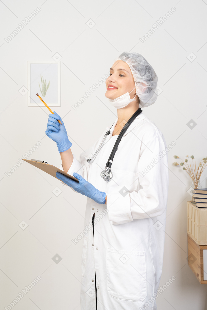 Vista di tre quarti di una giovane dottoressa sorridente che prende appunti sul suo tablet