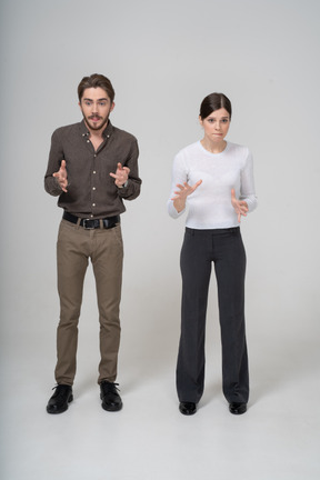 Vista frontal de um jovem casal gesticulando com roupas de escritório