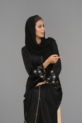 손가락으로 옆으로 가리키는 회의적인 아랍 여성