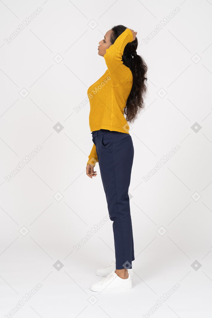 Side view of a girl in casual clothes posing with hand on head