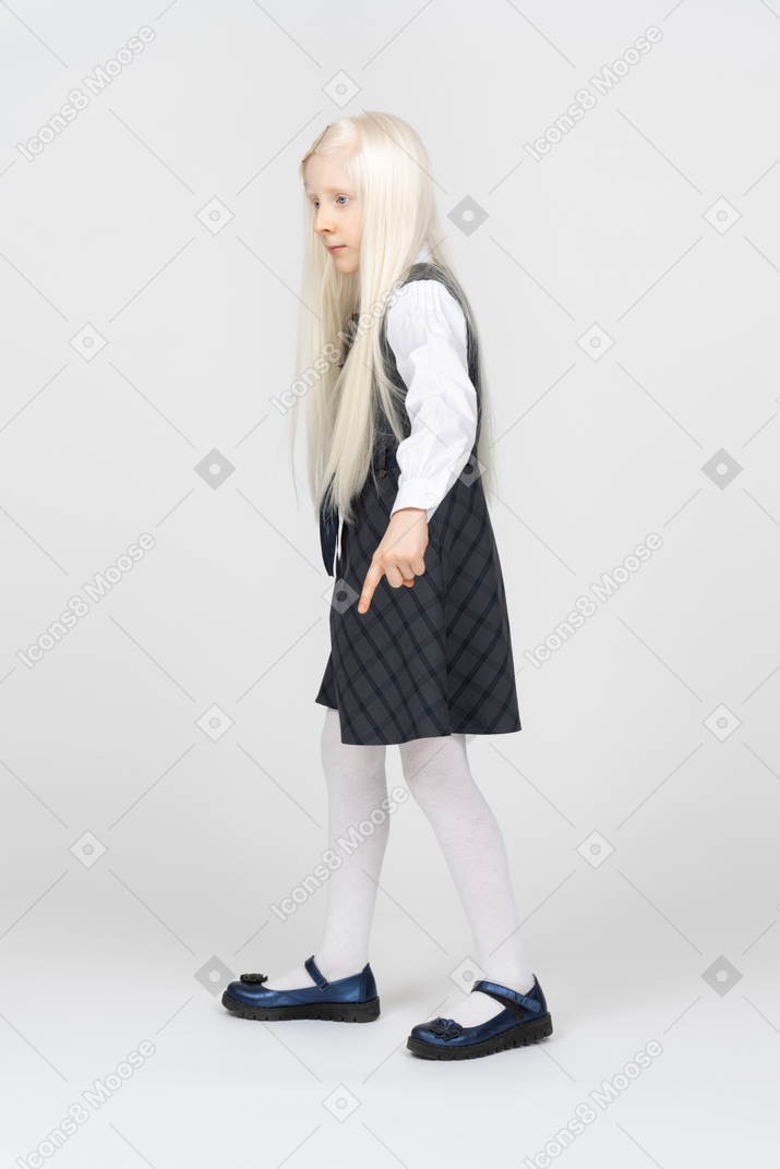 Side view of a schoolgirl pointing downwards