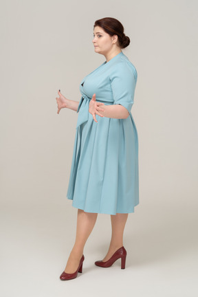 Vista laterale di una donna in abito blu in piedi con le braccia aperte