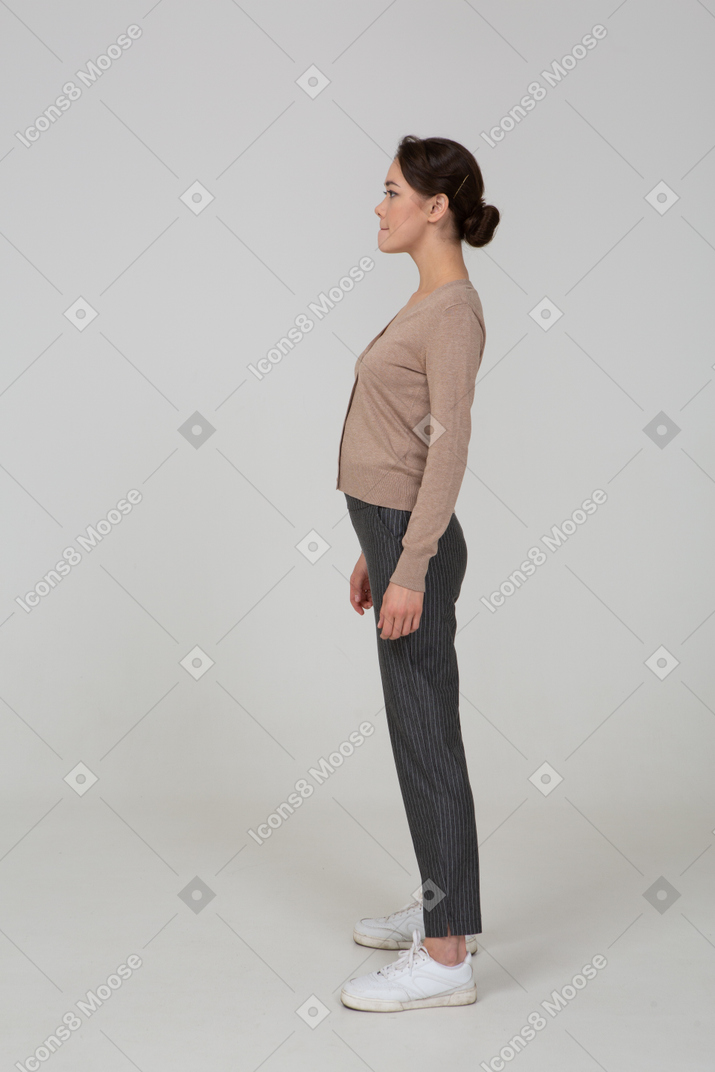 Vista laterale di una donna scontenta in pullover e pantaloni premendo le labbra