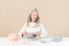 Mujer de edad tejiendo y mirando a un lado