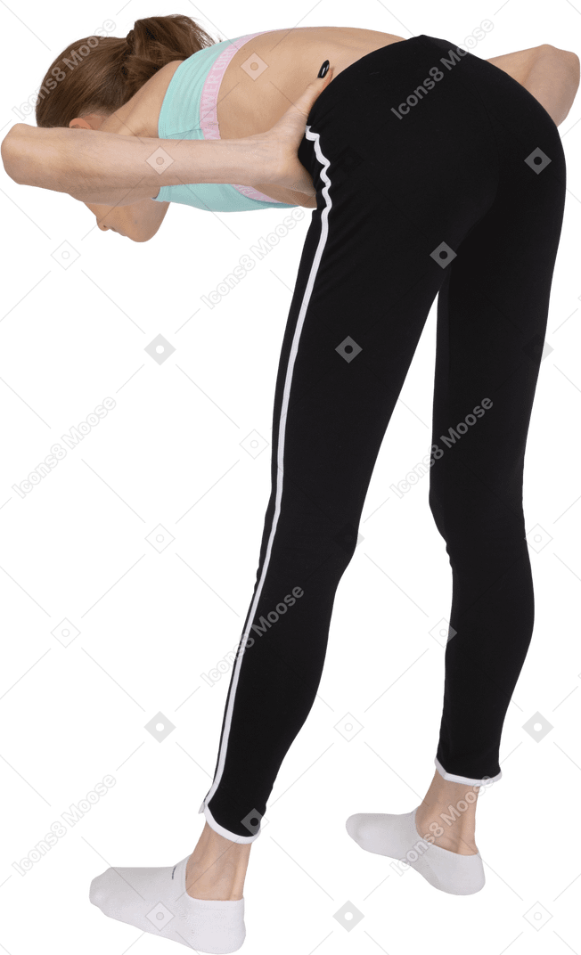 Vista posteriore di tre quarti di una ragazza adolescente in abbigliamento sportivo che mette le mani sui fianchi mentre si sporge in avanti
