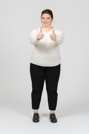 Mujer de talla grande en suéter blanco mostrando los pulgares para arriba