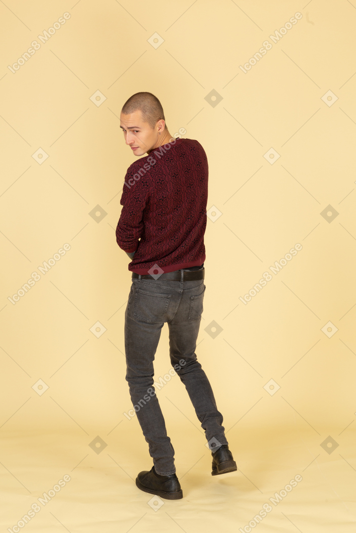 Back view of a young man in red pullover looking aside