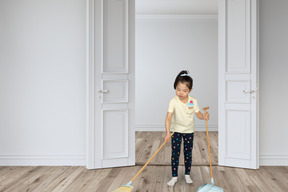 A little girl is cleaning the floor with a mop