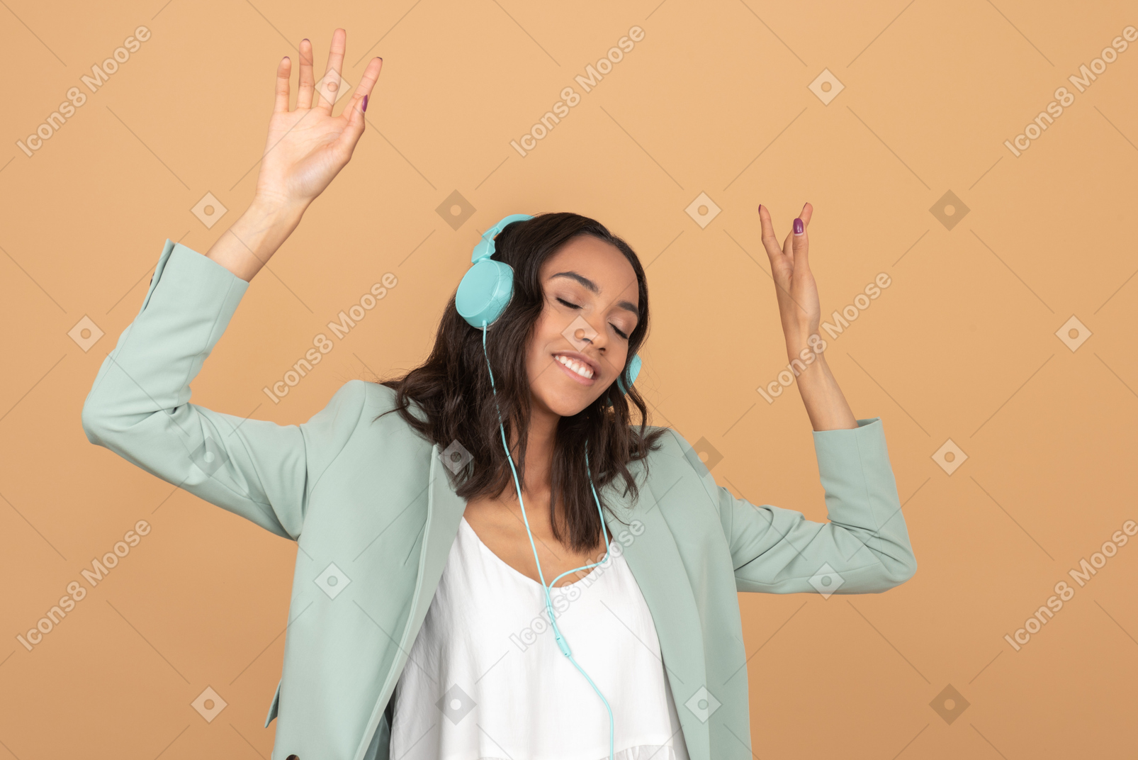 Chica joven atractiva escuchando música en auriculares y levantando sus manos