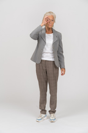 一位穿西装的老妇人透过手指看的前视图
