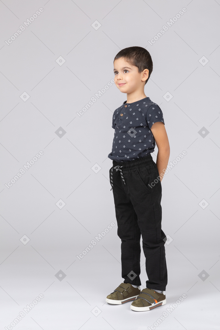 Front view of a cute boy posing with hands behind back