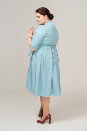 Грустная женщина в синем платье позирует в профиль