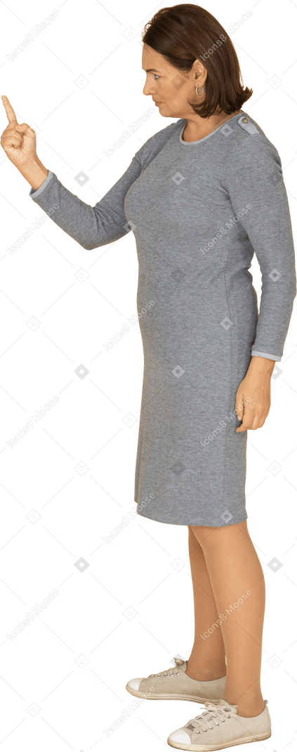 Vue latérale d'une femme en robe grise pointant vers le haut avec un doigt