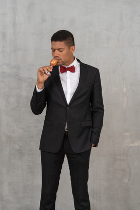 Young man with closed eyes drinking from a champagne glass