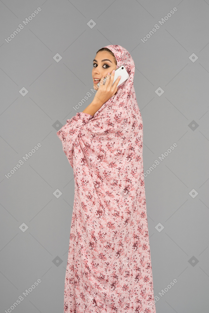 Mulher em um vestido de oração falando ao telefone