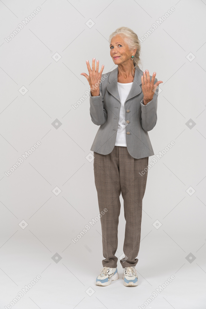 양복을 입고 손을 들고 서 있는 노부인의 전면 모습